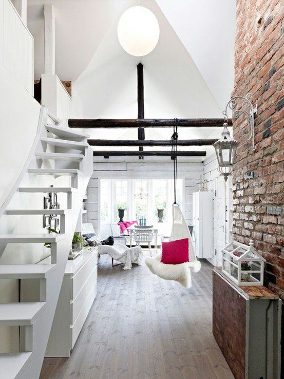 Белая мебель, высокие потолки и кирпичная стена создают по настоящему уютную атмосферу