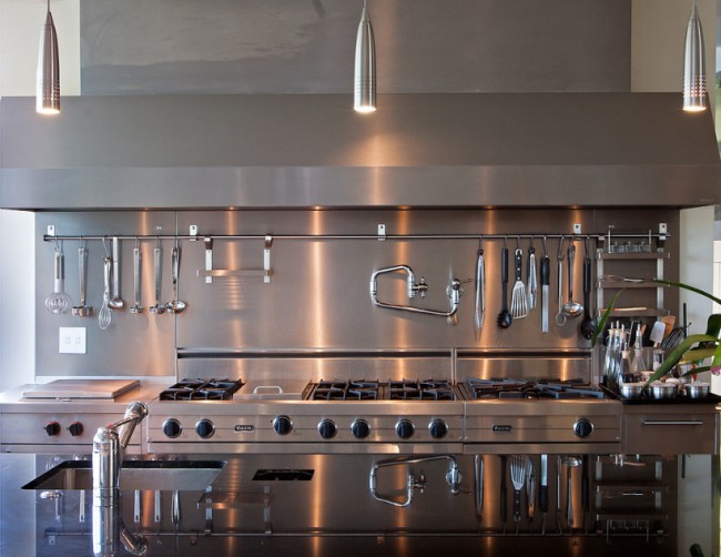 Длинный алюминиевый рейлинг на кухне со шкафами, фартуком и рабочей поверхностью преимущественно из шлифованного металла