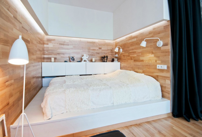 Современная спальня в скандинавском стиле с кроватью на подиуме и стенами отделанными ламинатом