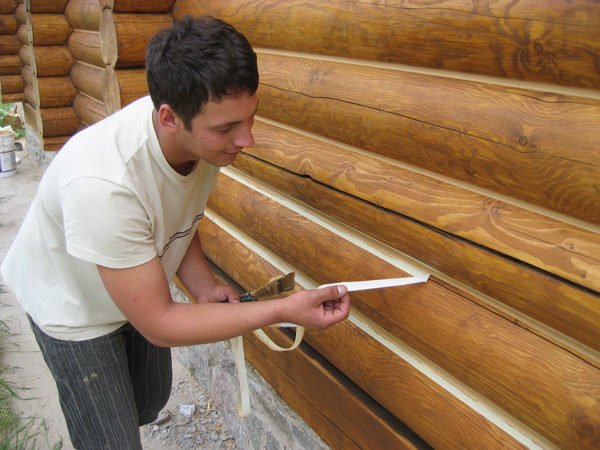 Процесс заделки швов между брёвнами деревянной постройки